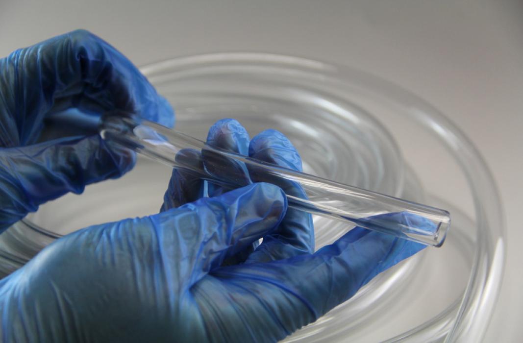 Transparenter Tygon®-Schlauch, der mit blauen Handschuhen gehalten wird.