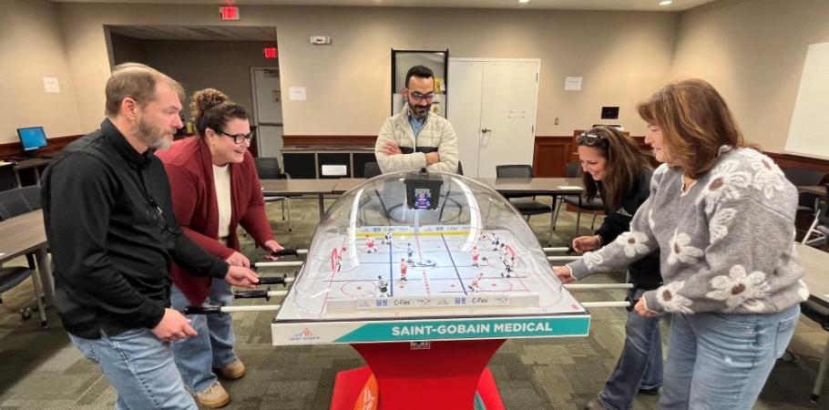 Saint-Gobain group gathered around the hockey bubble table, actively playing.